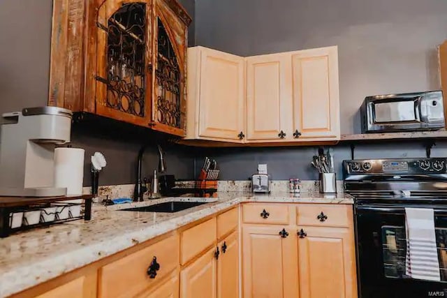 kitchen featuring light stone countertops, sink, light brown cabinets, and black range with electric cooktop