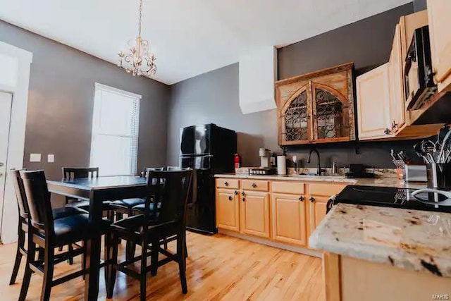 kitchen featuring sink, a chandelier, decorative light fixtures, black appliances, and light wood-type flooring