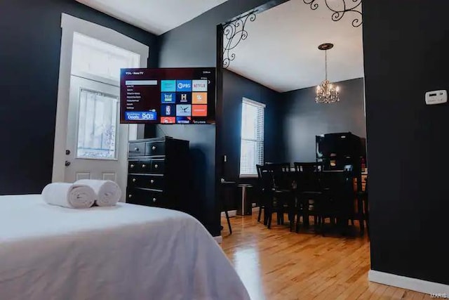 bedroom with wood-type flooring and an inviting chandelier