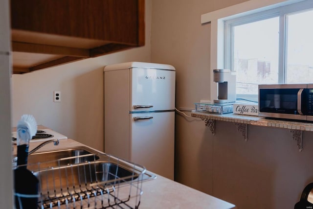 kitchen with beam ceiling, white fridge, sink, and a breakfast bar