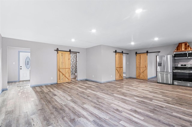 unfurnished living room with light wood-type flooring and a barn door