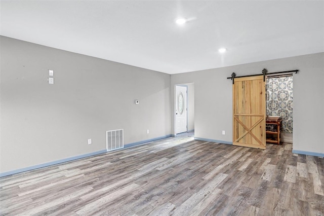 empty room with a barn door and light hardwood / wood-style floors