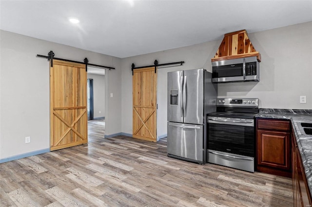 kitchen featuring a barn door, stainless steel appliances, and light wood-type flooring