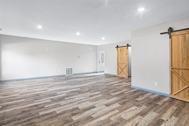 empty room with hardwood / wood-style flooring and a barn door