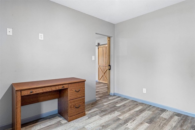 unfurnished office with light wood-type flooring and a barn door