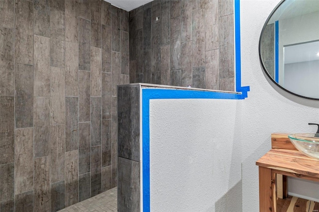 bathroom featuring tiled shower and vanity