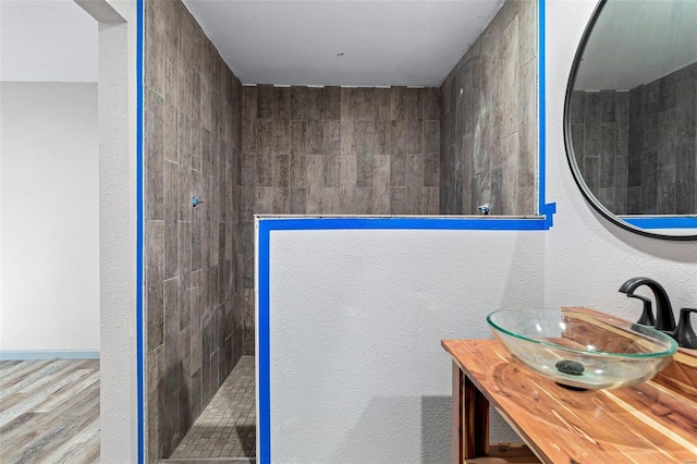 bathroom with a tile shower, hardwood / wood-style floors, and vanity