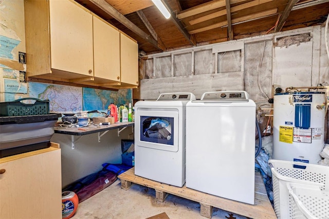 clothes washing area featuring electric water heater, cabinets, and washer and dryer