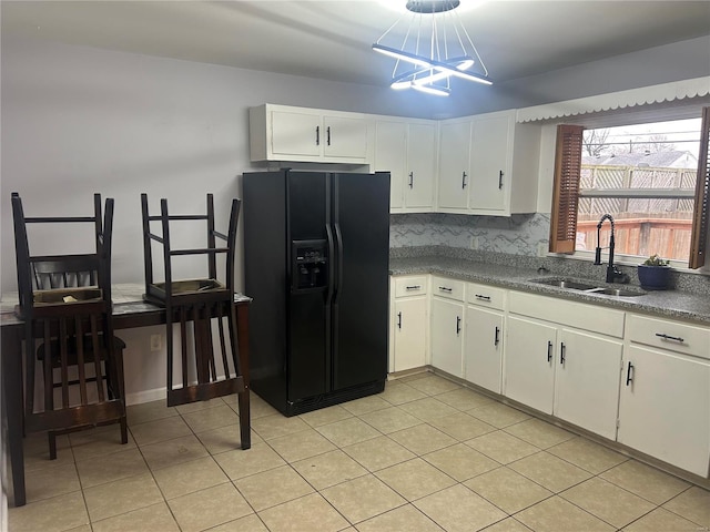 kitchen featuring backsplash, black fridge, sink, white cabinets, and a chandelier