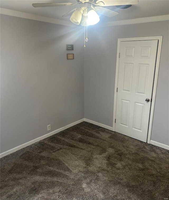 empty room featuring dark colored carpet, ceiling fan, and ornamental molding