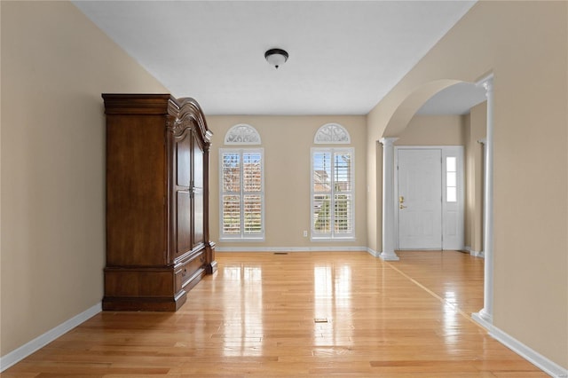 foyer entrance featuring light hardwood / wood-style flooring and ornate columns