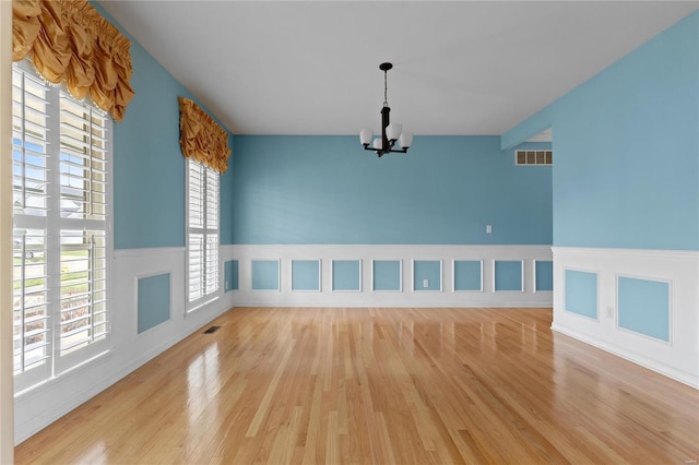 unfurnished room with light wood-type flooring and an inviting chandelier