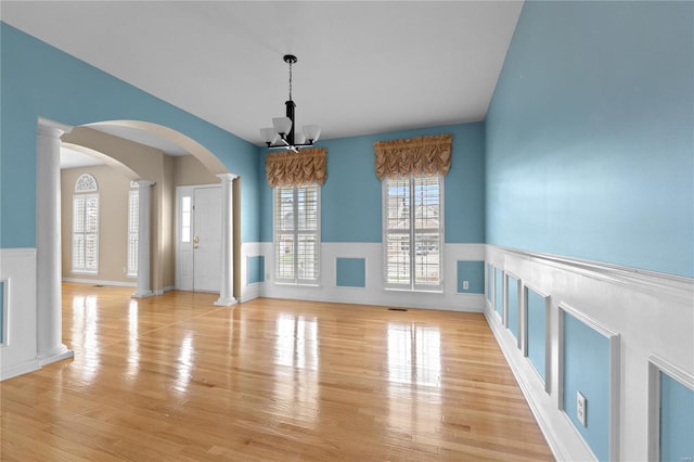 interior space featuring a notable chandelier, ornate columns, and light hardwood / wood-style flooring