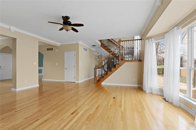 unfurnished living room with ceiling fan, light wood-type flooring, ornamental molding, and plenty of natural light