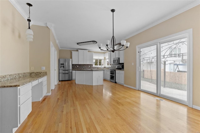 kitchen with white cabinetry, stainless steel appliances, decorative light fixtures, decorative backsplash, and ornamental molding