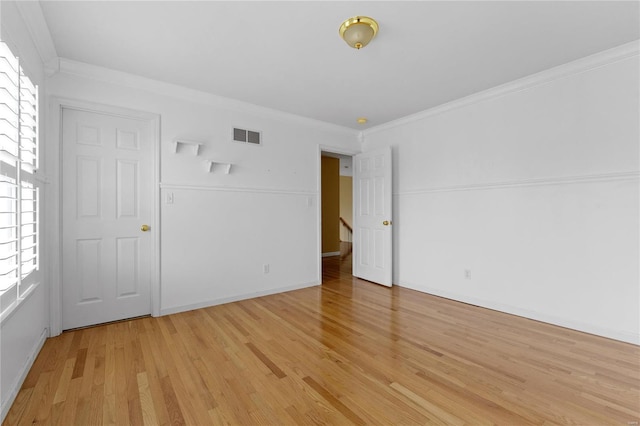 empty room featuring crown molding and light hardwood / wood-style flooring