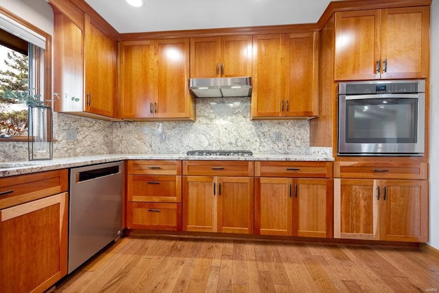 kitchen with light stone counters, light hardwood / wood-style flooring, and appliances with stainless steel finishes