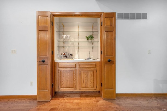 bar featuring light hardwood / wood-style flooring and sink