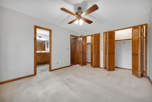 unfurnished bedroom with ensuite bathroom, ceiling fan, light colored carpet, and multiple closets