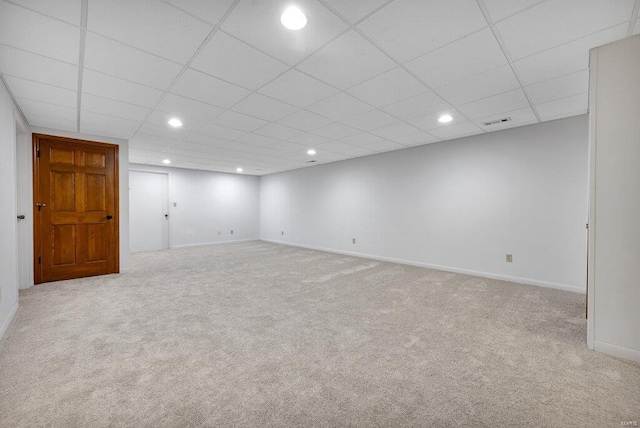 basement with a drop ceiling and light colored carpet