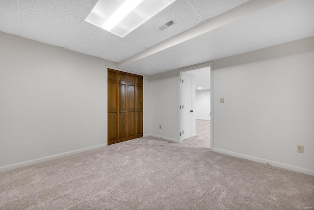 unfurnished bedroom featuring light carpet, a paneled ceiling, and a closet