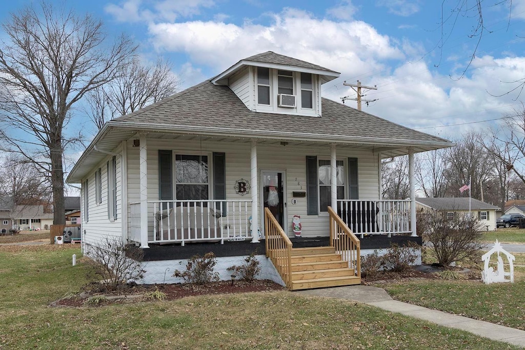 bungalow-style home with a porch, a front yard, and cooling unit