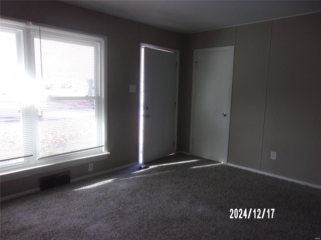 carpeted empty room featuring visible vents