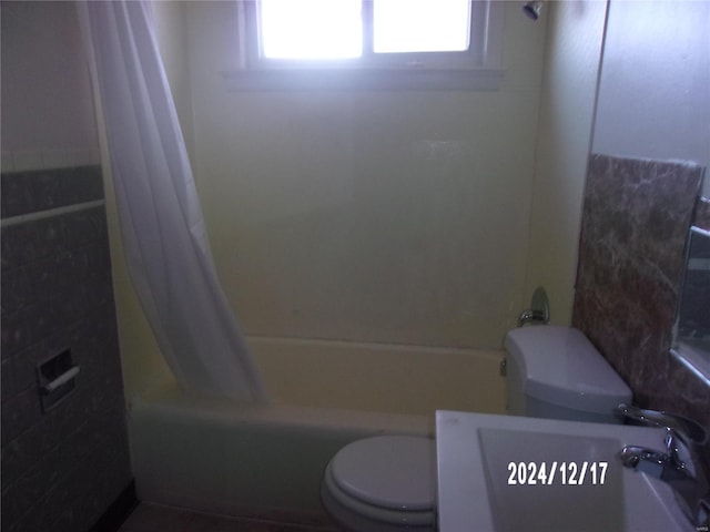 bathroom featuring toilet and shower / tub combo with curtain