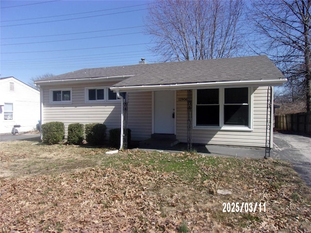 view of front of property featuring roof with shingles and fence