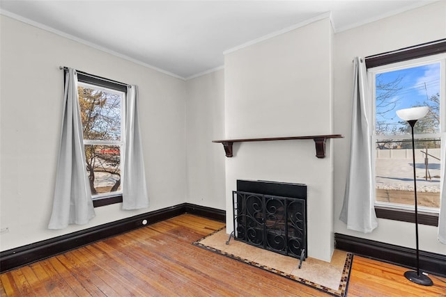 unfurnished living room with a baseboard heating unit, ornamental molding, and wood-type flooring