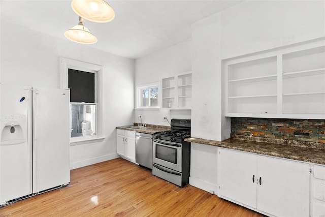 kitchen with sink, white cabinets, dark stone countertops, light hardwood / wood-style flooring, and appliances with stainless steel finishes