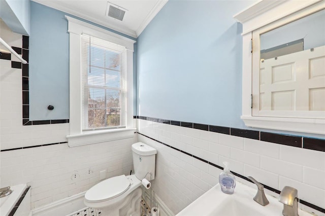 bathroom with toilet, tile walls, ornamental molding, and sink