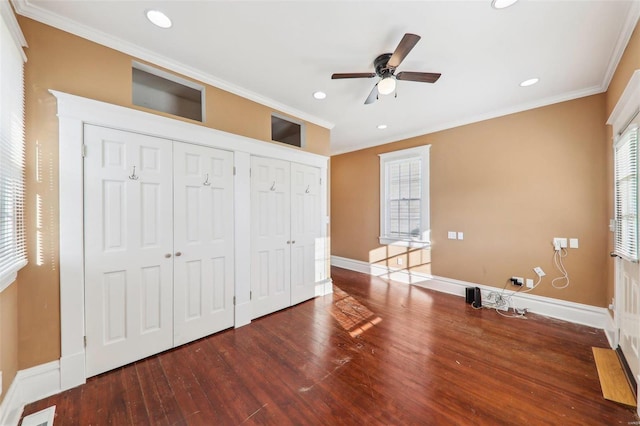 unfurnished bedroom with ceiling fan, hardwood / wood-style floors, two closets, and ornamental molding