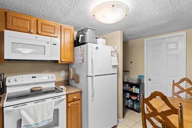 kitchen featuring white appliances, a textured ceiling, and light tile patterned floors