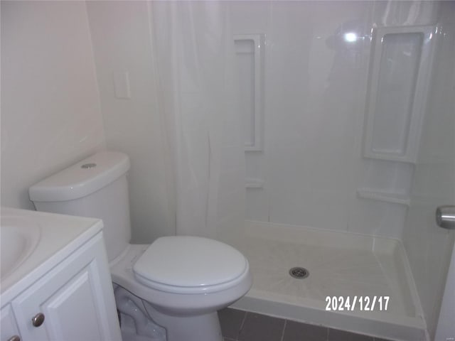 bathroom featuring tile patterned floors, toilet, vanity, and walk in shower