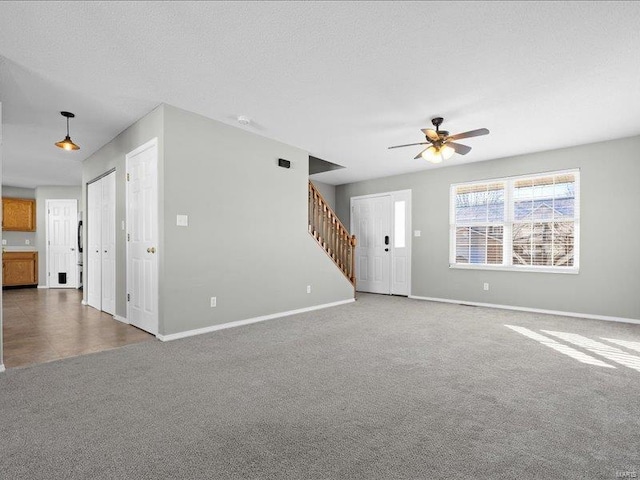 unfurnished living room with ceiling fan, a textured ceiling, and dark colored carpet