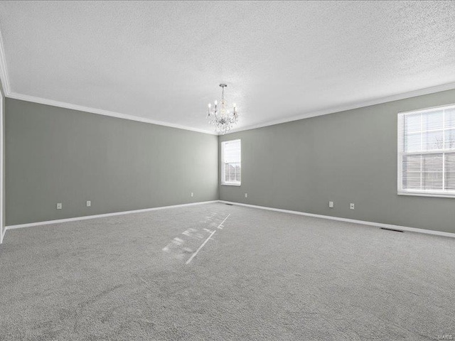 spare room with carpet, a notable chandelier, crown molding, and a textured ceiling