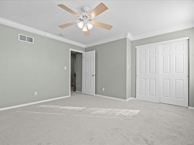 unfurnished bedroom featuring a closet, ceiling fan, crown molding, and light colored carpet