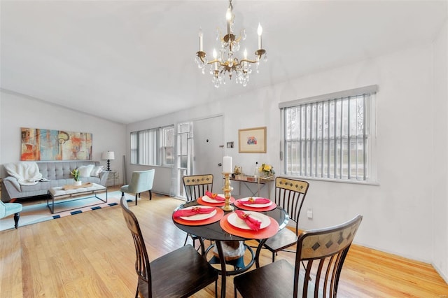 dining room featuring a chandelier, vaulted ceiling, and light hardwood / wood-style flooring