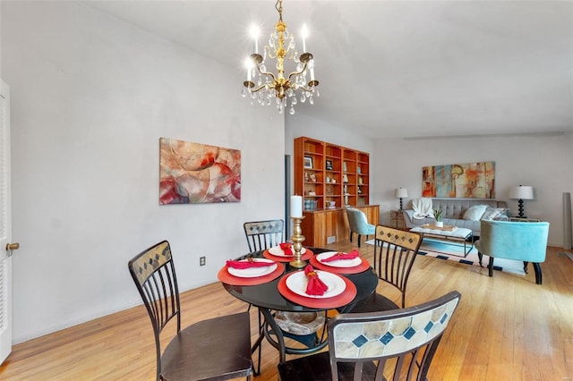 dining space with light hardwood / wood-style floors and an inviting chandelier