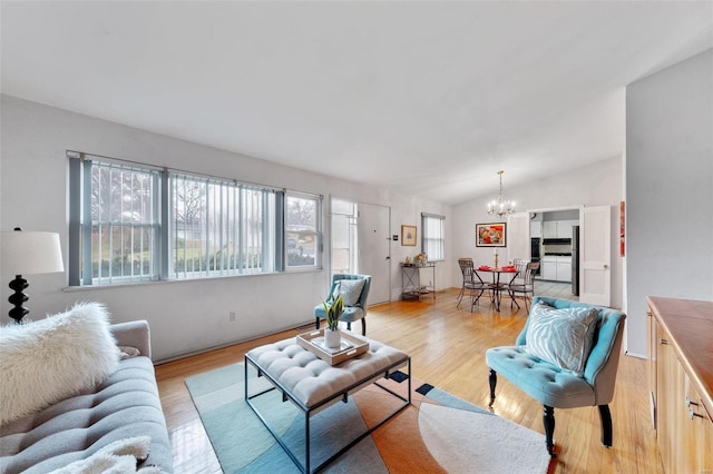 living room with light hardwood / wood-style floors, an inviting chandelier, a wealth of natural light, and lofted ceiling