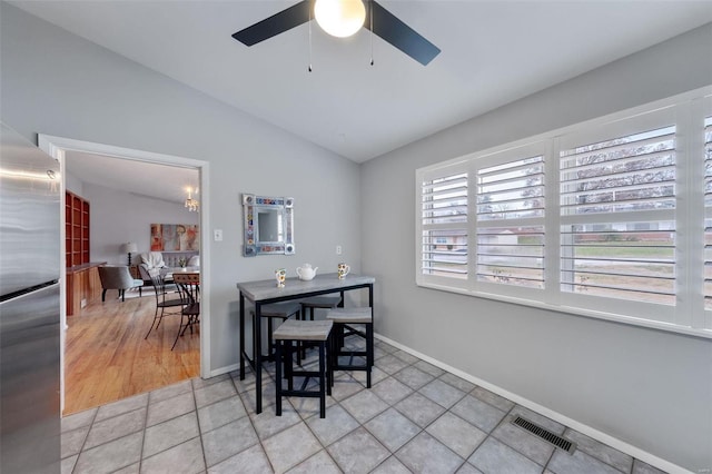 dining room with ceiling fan, light hardwood / wood-style floors, and vaulted ceiling