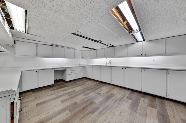 basement featuring light wood-type flooring and a paneled ceiling