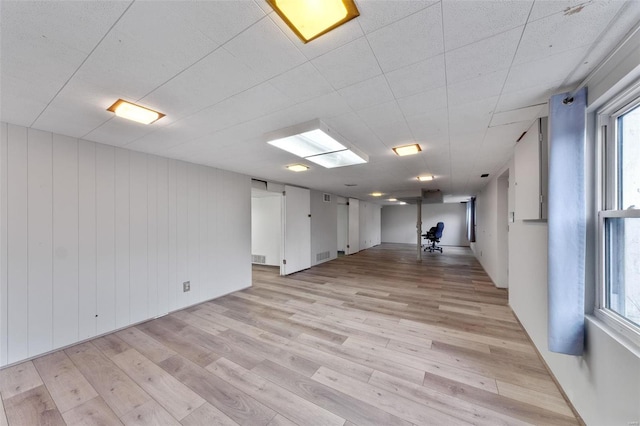 spare room with light hardwood / wood-style flooring and wooden walls