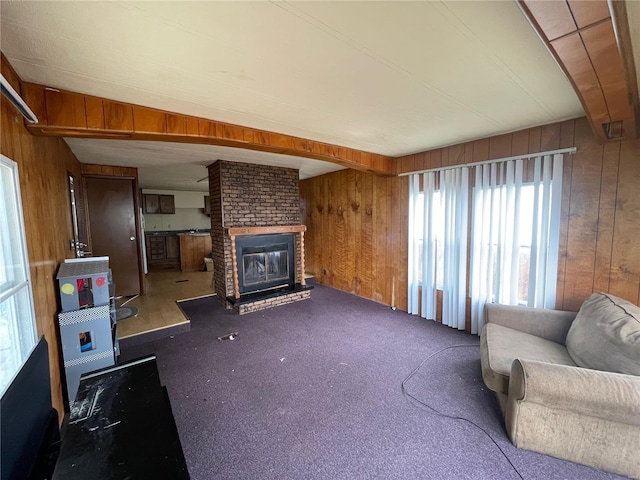 living room with wood walls, carpet, and a brick fireplace