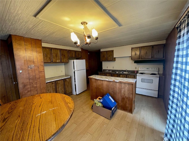 kitchen featuring sink, an inviting chandelier, white appliances, a kitchen island, and light wood-type flooring