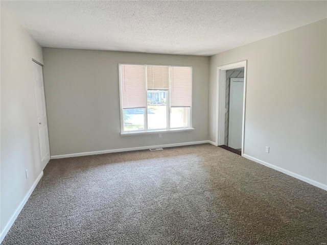 carpeted empty room with a textured ceiling