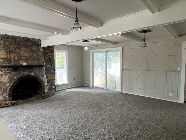 unfurnished living room with beam ceiling, wooden walls, a fireplace, and carpet floors