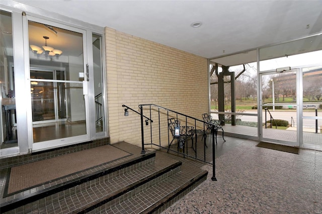 workout room with a notable chandelier, floor to ceiling windows, and brick wall