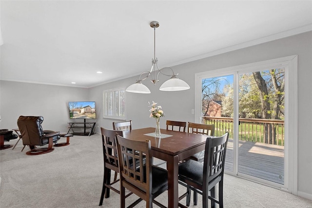 dining area featuring light carpet, ornamental molding, and a notable chandelier